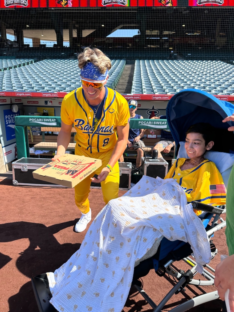 Ricky receiving a special pizza from the Savannah Bananas during a surprise outing organized by Baller Dreams Foundation.