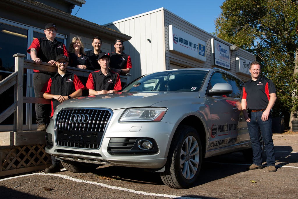Image of the shop’s team standing beside a silver Audi customer shuttle vehicle in front of the Wendell Taylor’s Garage building, showcasing their professional crew and welcoming facility. Image of the shop’s team standing beside a silver Audi customer shuttle vehicle in front of the Wendell Taylor’s Garage building, showcasing their professional crew and welcoming facility.